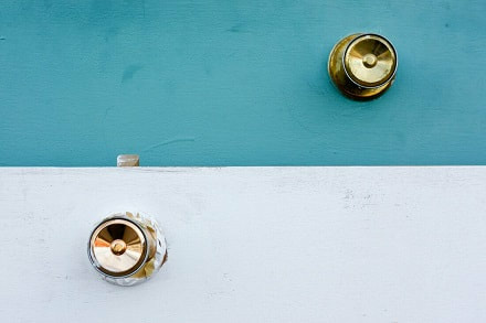 Two doorknobs against solid colours.
